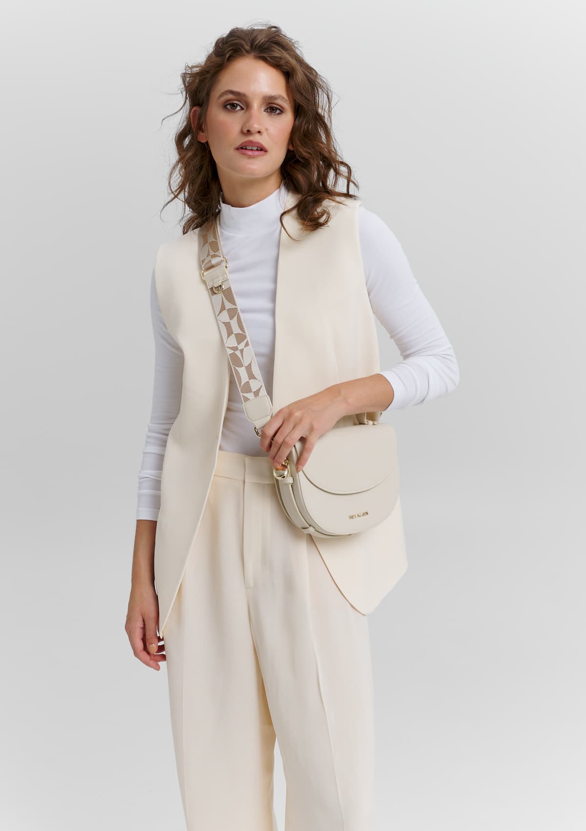 Tragebild mit Model auf neutralem Hintergrund des Produktes Iconic Strap in der Farbe Crema-Sand