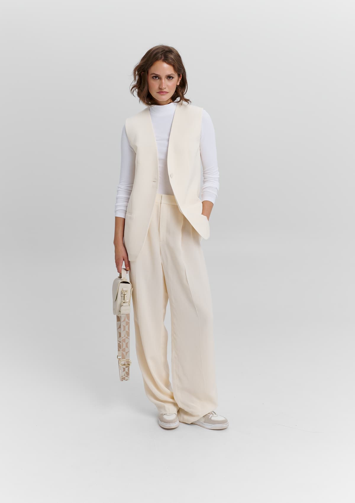Tragebild mit Model auf neutralem Hintergrund des Produktes Iconic Strap in der Farbe Crema-Sand