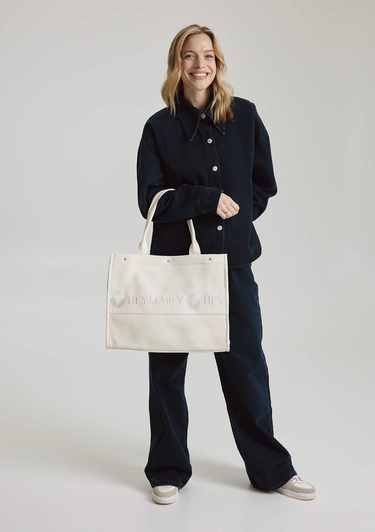 Tragebild mit Model auf neutralem Hintergrund des Produktes Signature Bag in der Farbe Crema