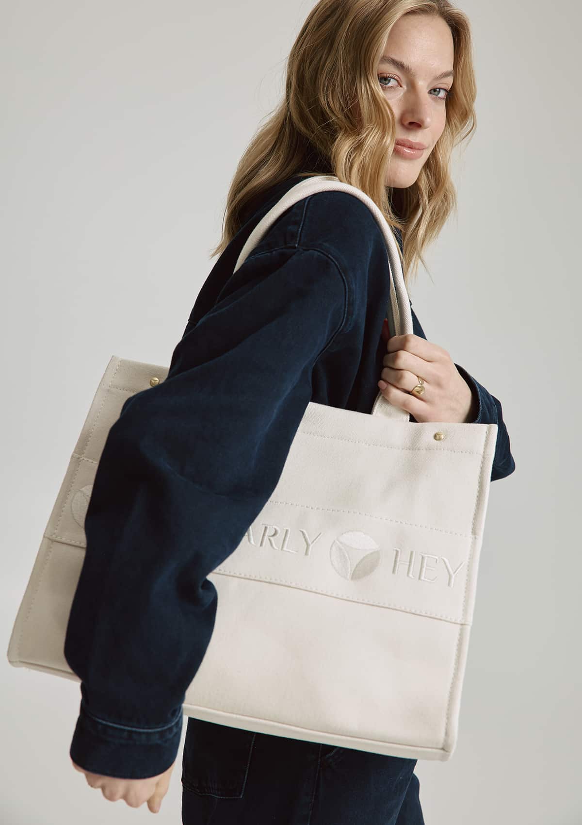 Tragebild mit Model auf neutralem Hintergrund des Produktes Signature Bag in der Farbe Crema