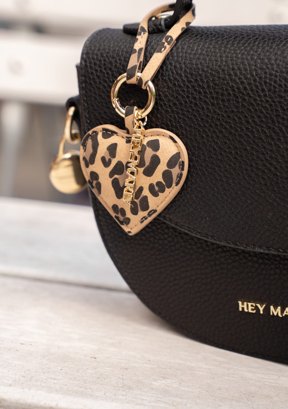 Tragebild mit Model auf neutralem Hintergrund des Produktes Heart Tassle Charm in der Farbe Leo Sand