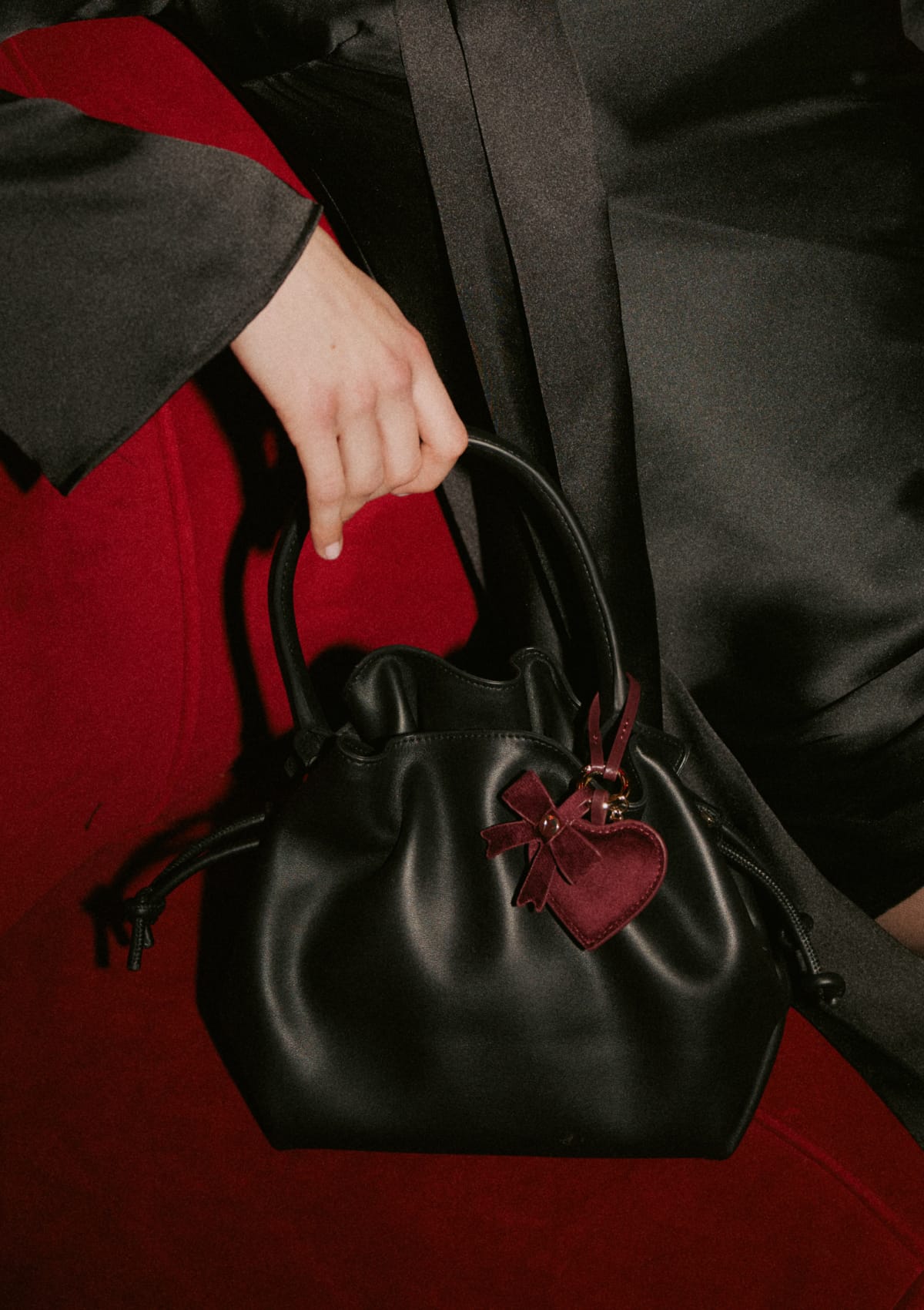 Tragebild mit Model auf neutralem Hintergrund des Produktes Heart & Bow Charm in der Farbe Berry