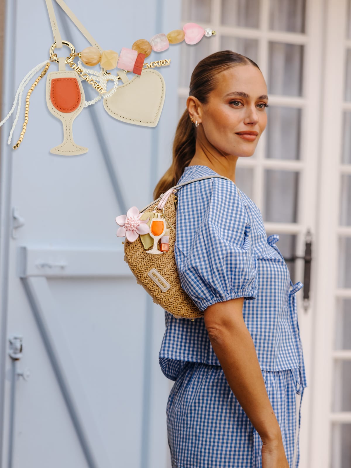 Model vor blauem Hintergrund mit einer Tasche und mehreren Bag Charms