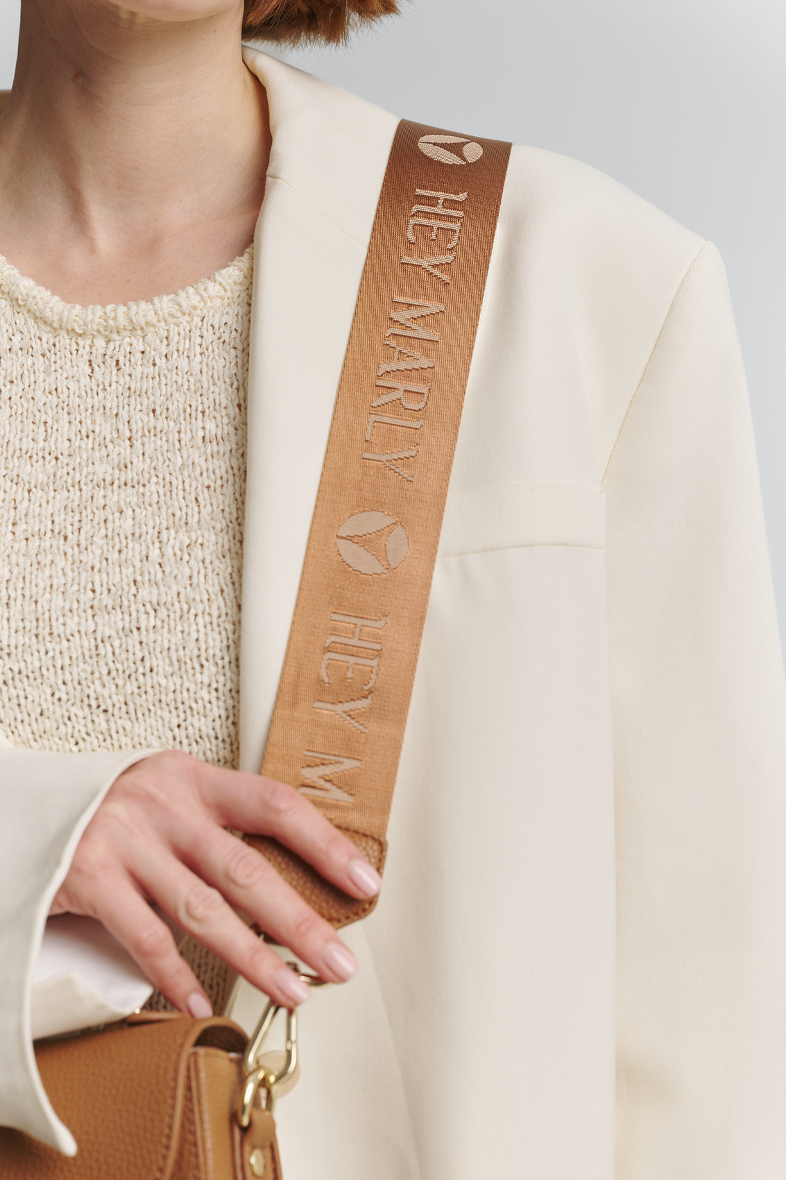 Tragebild mit Model auf neutralem Hintergrund des Produktes Signature Strap in der Farbe Cognac