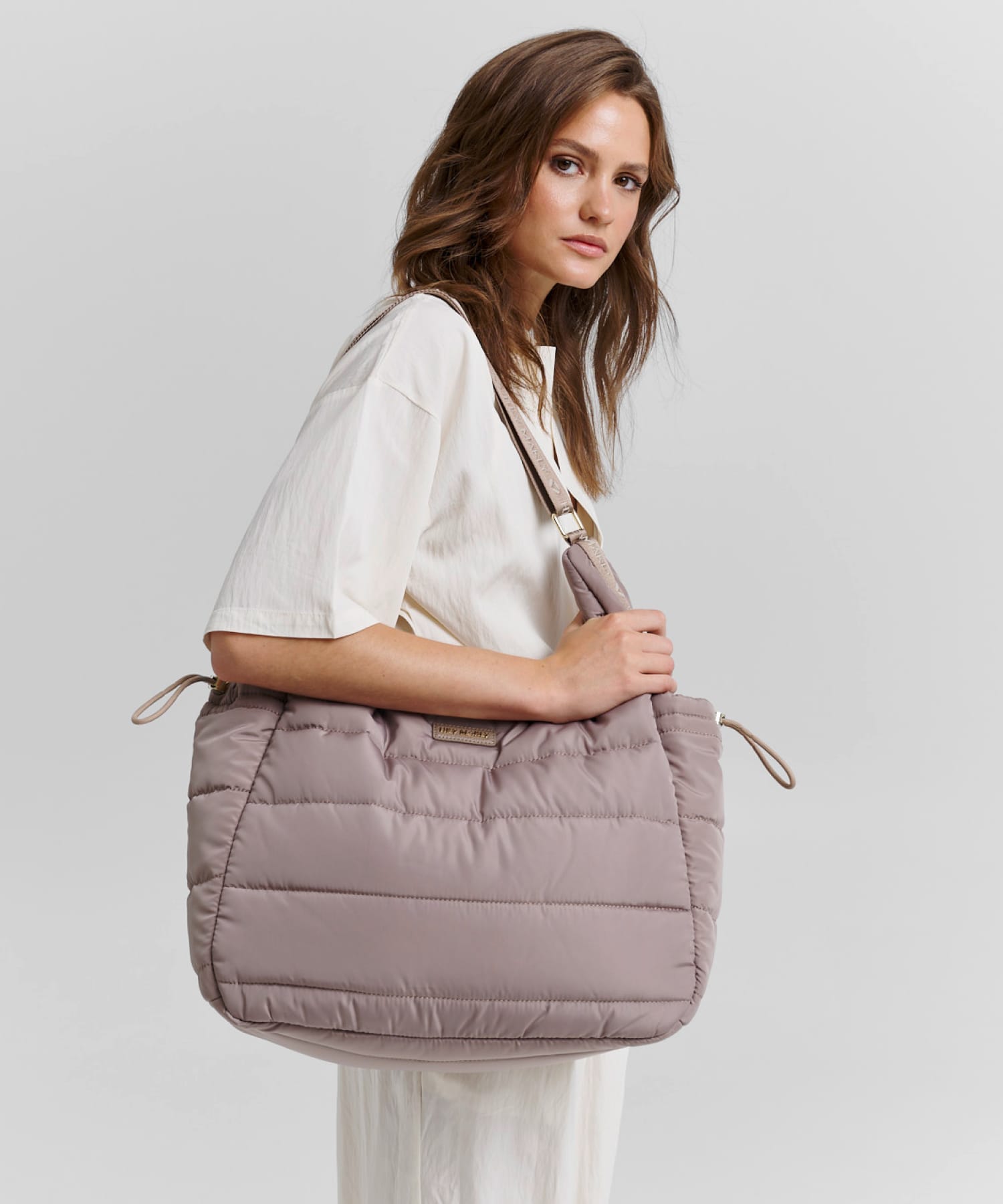 Model mit Puffy Buddy Tasche vor neutralem Hintergrund und dem Text 